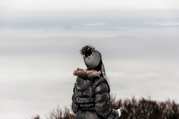 Femme portant une doudoune et un chapeau dans la forêt d'hiver