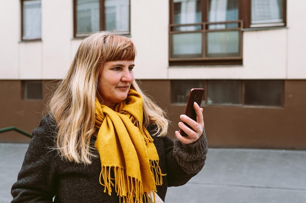 Une femme portant une écharpe jaune regarde son téléphone