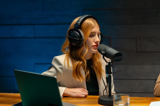 Photo une femme portant des écouteurs est assise à un bureau devant un microphone prête à parler lors d'un événement