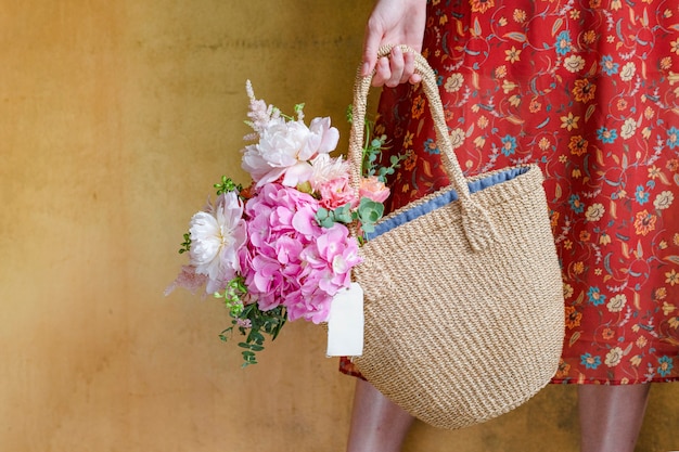 Femme portant des fleurs dans un sac en osier