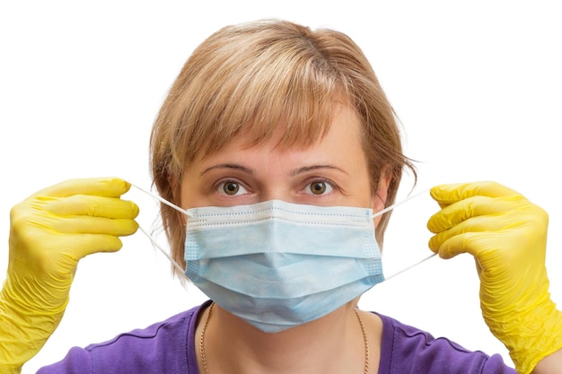 Une femme portant des gants en latex met un masque médical comme protection contre les virus en suspension dans l'air