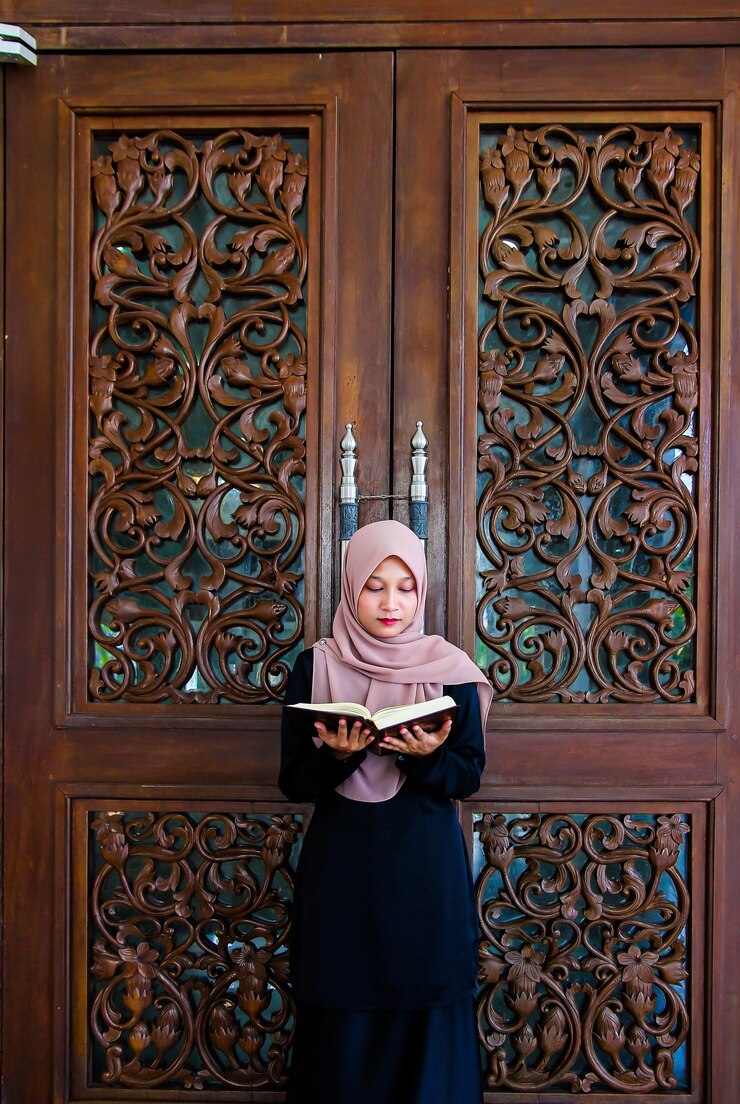 Photo une femme portant un hijab en lisant un livre sacré contre une porte en bois