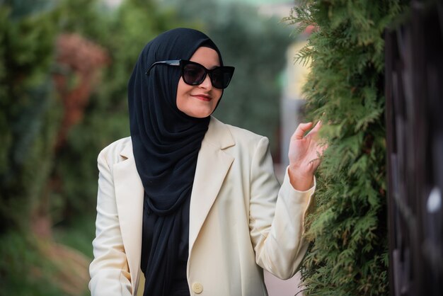 Photo une femme portant un hijab et des lunettes de soleil se tient dans un parc.