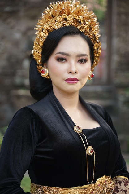Femme portant une kebaya balinaise noire et des bijoux violets à l'extérieur