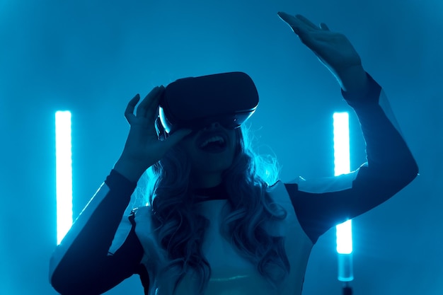 Femme portant des lunettes de réalité virtuelle concept futuriste silhouette d'une jeune femme du futur sur un fond bleu gesticulant