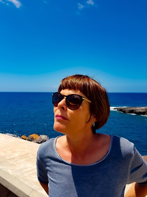 Photo une femme portant des lunettes de soleil contre la mer bleue