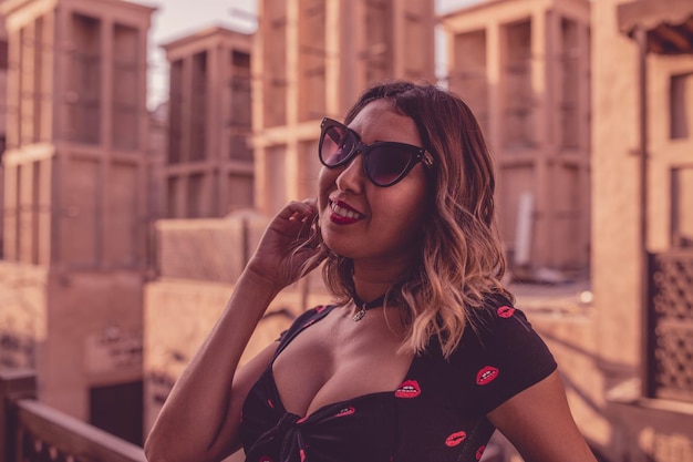Une femme portant des lunettes de soleil debout contre des bâtiments