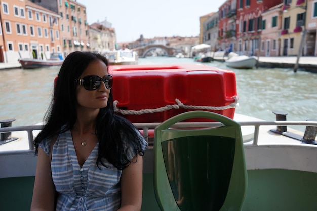Photo femme portant des lunettes de soleil détournant le regard alors qu'elle est assise dans un bateau sur un canal