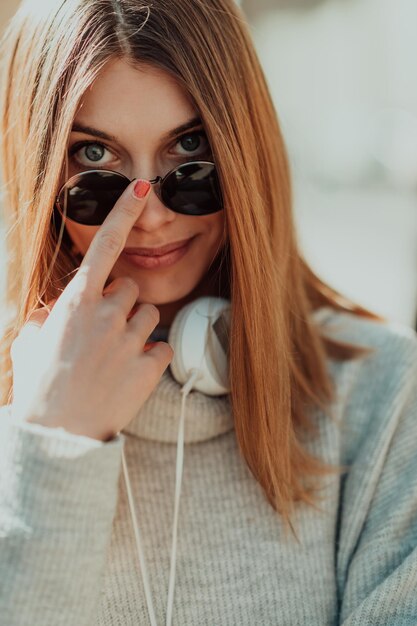 une femme portant des lunettes de soleil profite d'une promenade dans la ville tout en écoutant de la musique sur ses écouteurs