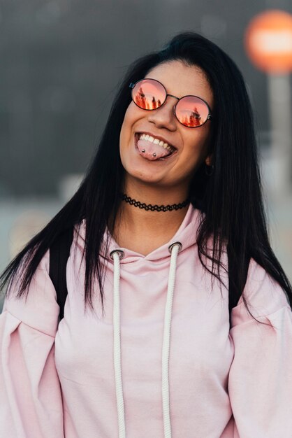 Femme portant des lunettes de soleil et souriant posant en plein air