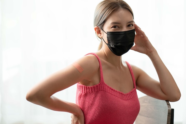 Femme portant un masque et un bras avec un bandage montrant son bras après avoir reçu le vaccin