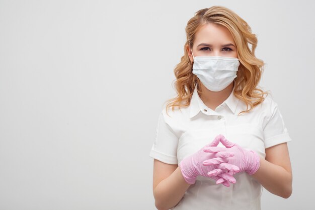 Une femme portant un masque et des gants au look amical se trouve à droite de l'espace de texte. Concept de mesures préventives contre les coronovirus, protection contre les infections, soins médicaux.