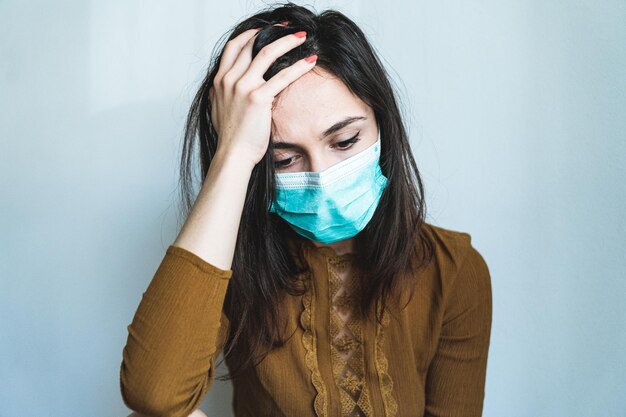 Femme portant un masque avec la main dans les cheveux sur un fond blanc
