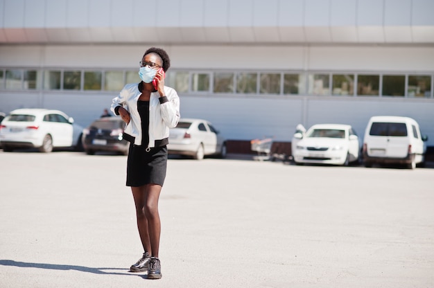 femme portant un masque médical jetable et des gants marcher en plein air et parler au téléphone pendant la période épidémique.