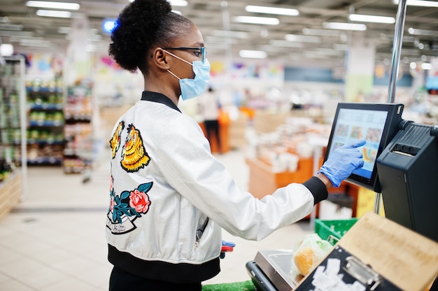 femme portant un masque médical jetable et des gants shopping dans un supermarché lors d'une épidémie de pandémie de coronavirus.