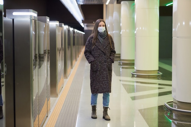 Une femme portant un masque médical pour éviter la propagation du coronavirus marche en attendant un train sur le quai du métro