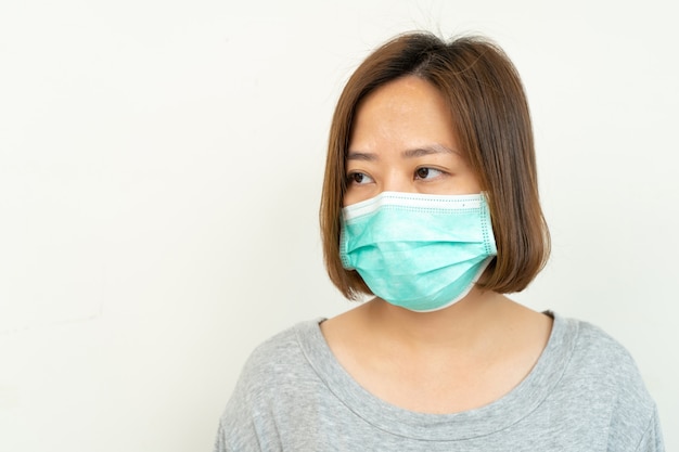 Femme portant un masque pour protéger le coronavirus sur blanc. Pollution de l'air, concept environnemental.