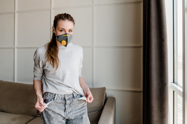 Femme portant un masque de protection à la maison avec des poches vides