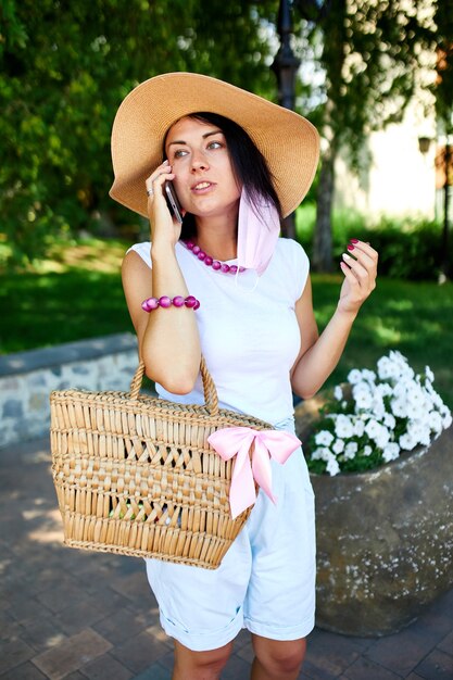 Femme portant un masque rose et parlant avec quelqu'un sur son téléphone portable parc à pied en plein air, jeune femme avec le téléphone portable, pandémie, épidémie de coronavirus, deux vagues