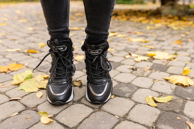 Une femme portant une paire de chaussures de course Nike se dresse sur une allée en brique.