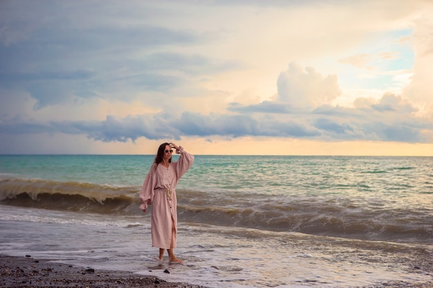 Femme portant sur la plage, profitant des vacances d'été en regardant la mer