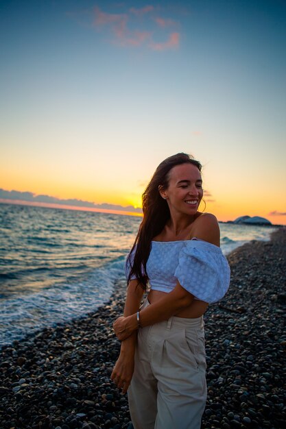 Femme portant sur la plage, profitant des vacances d'été en regardant la mer