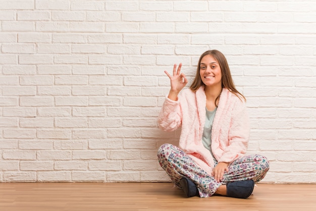 Femme portant un pyjama gai et confiant faisant le geste ok