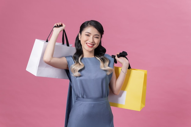 Femme portant une robe bleue sur fond heureux de faire du shopping tenant des sacs colorés