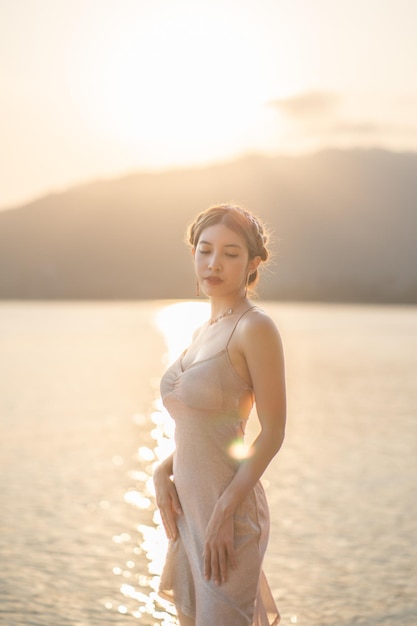 Femme portant une robe courte à paillettes profitant d'un moment romantique au coucher du soleil à la plage