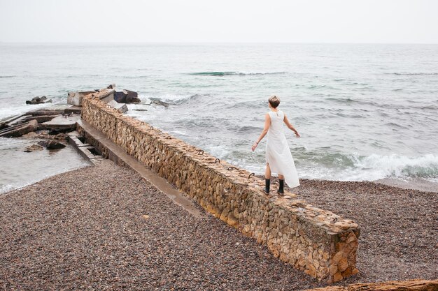 Femme portant une robe marchant près de la mer en automne