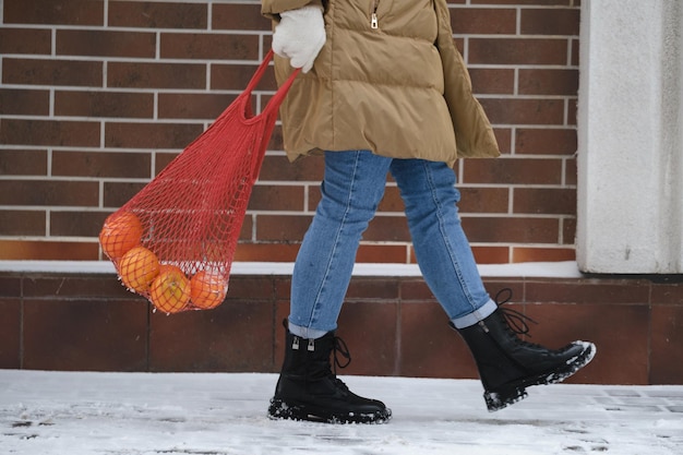 Femme portant un sac écologique réutilisable avec des oranges de la boutique