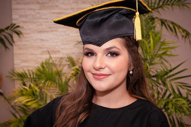 Photo une femme portant une toge et un bonnet de graduation sourit à la caméra.