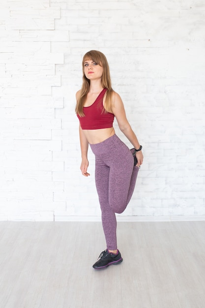 Femme portant des vêtements sportifs colorés et faire des exercices pour les jambes pour étirer les muscles.