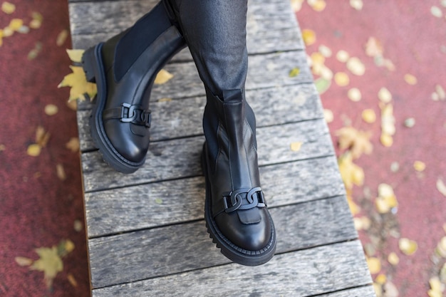 Une femme porte des bottes noires avec un logo gg sur le côté.