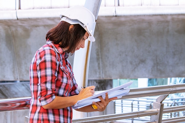 Une femme porte un chapeau de sécurité blanc travaille sur un chantier de construction