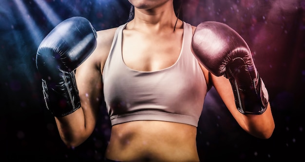 Une femme porte des gants de boxe pour se battre ou faire de l'exercice