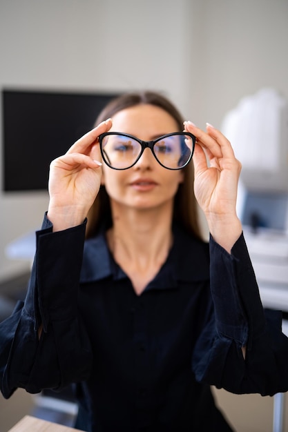 Femme porte des lunettes dioptriques modernes dans les mains de la femme Concept de correction de la vue Gros plan