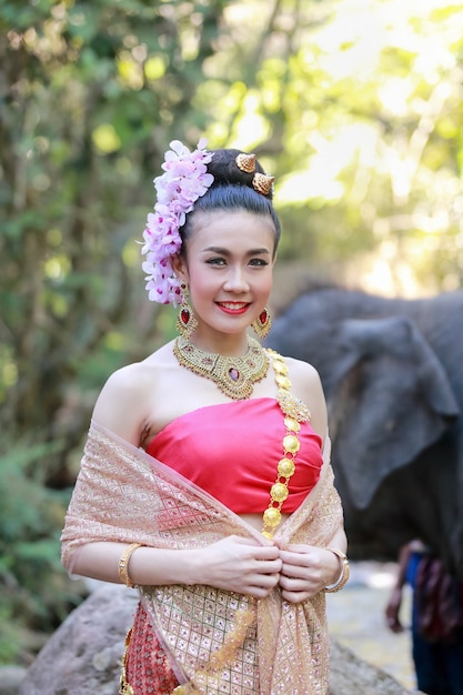 Une femme porte une robe thaïlandaise avec son éléphant