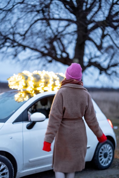 Une femme porte un sapin de Noël en voiture