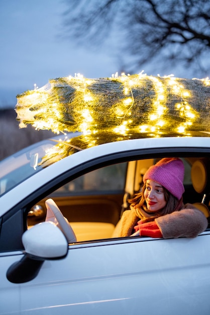 Une femme porte un sapin de Noël en voiture