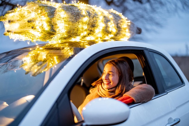 Une femme porte un sapin de Noël en voiture