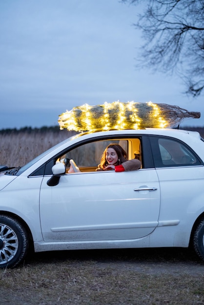 Une femme porte un sapin de Noël en voiture