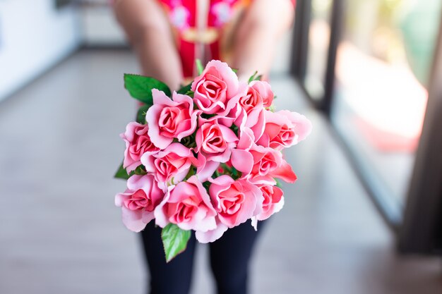 Femme porter une chemise rouge tenant un bouquet de roses roses. Concept de la Saint-Valentin