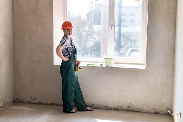 Femme posant avec un rouleau pour la peinture et un seau de teinte