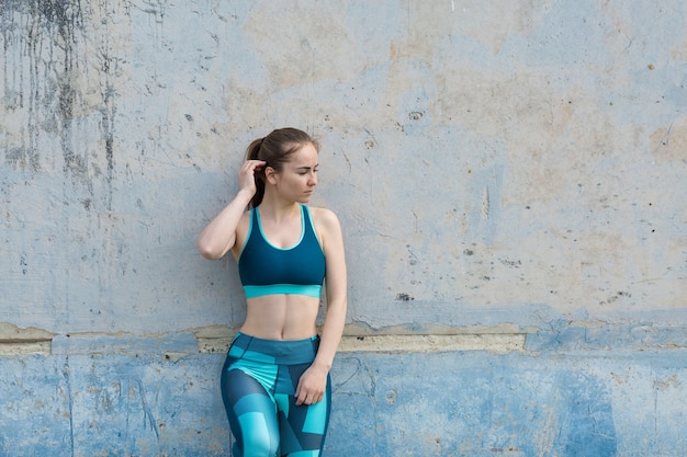 Femme posant en tenue de sport sur fond de ciel. La partie médiane du corps.