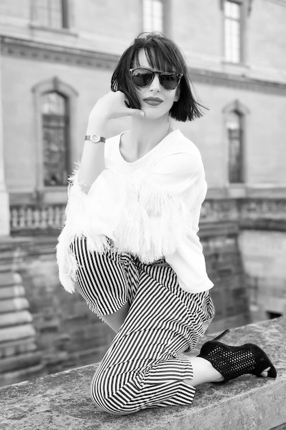 Femme pose sur une clôture en pierre sur la façade de la maison