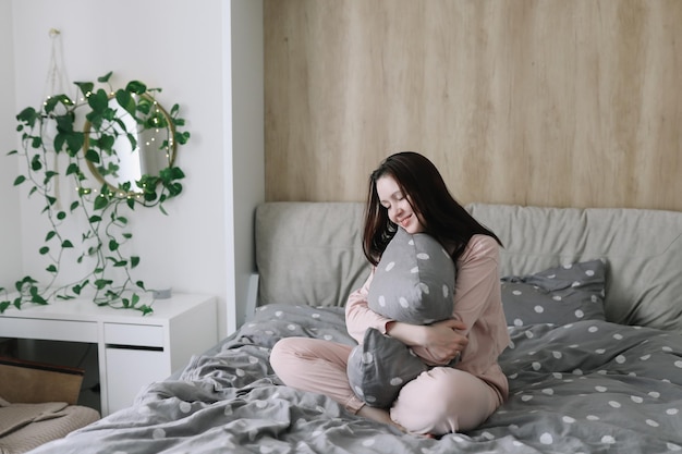 Femme Positive Avec Oreiller Assis Dans Son Lit à La Maison Doux Rêves Bonjour Nouveau Jour Week-end Vacances Concept