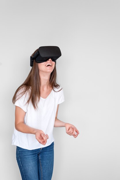 Femme positive souriante portant un casque de lunettes de réalité virtuelle, boîte vr. Connexion, technologie, nouvelle génération, concept de progrès. Fille essayant de toucher des objets en réalité virtuelle. Studio tourné sur gris