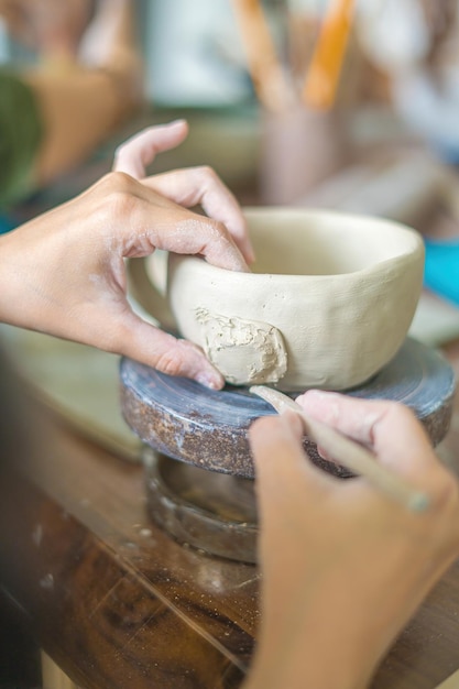 Femme potier travaillant sur la roue des potiers faisant un pot en céramique à partir d'argile dans le concept d'art de l'atelier de poterie