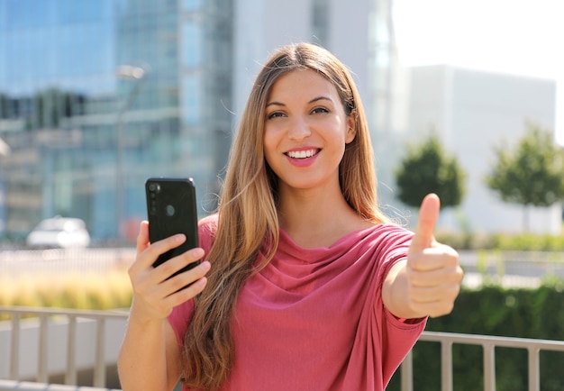 Femme pouces vers le haut avec smartphone à la main